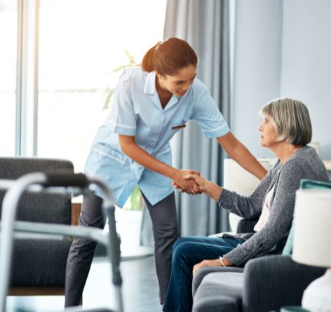 Woman helping elder patient stand up