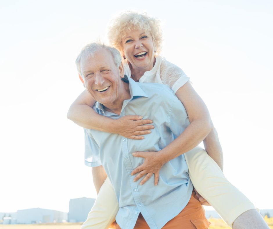older man playfully carrying older woman on his back