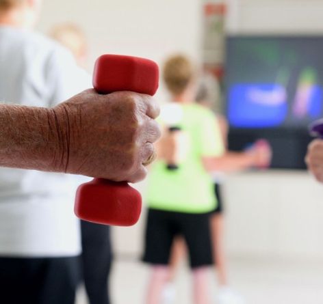 Senior holding dumbells in fitness class