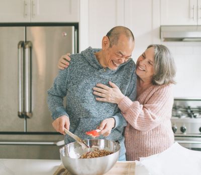 senior couple happily preparing meal in kitchen