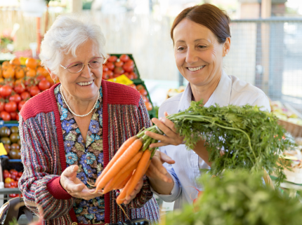 senior woman who is receiving assisted living services grocery shopping with her caregiver