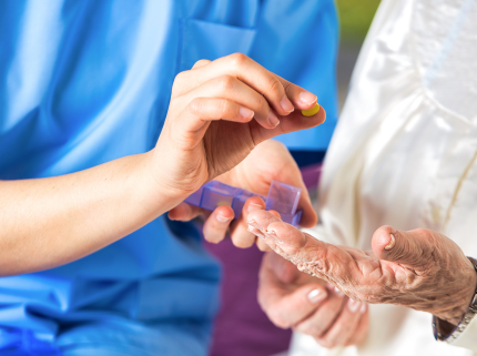 An assisted living caregiver giving medicine to senior