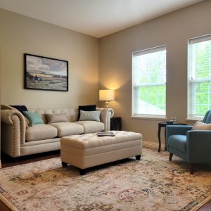 Senior independent living apartment family room with beige couch and ottoman and teal blue chair