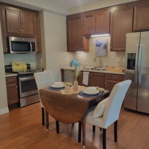 Senior apartment living kitchen with two-seat dining table, refrigerator, and oven