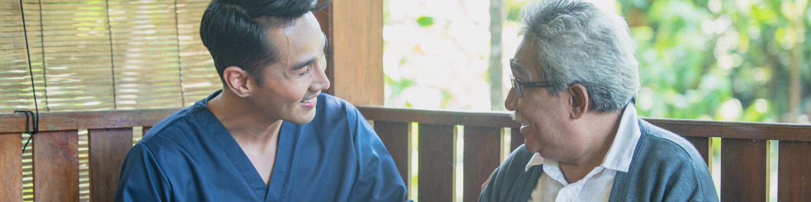Caregiver sitting next to an elderly man