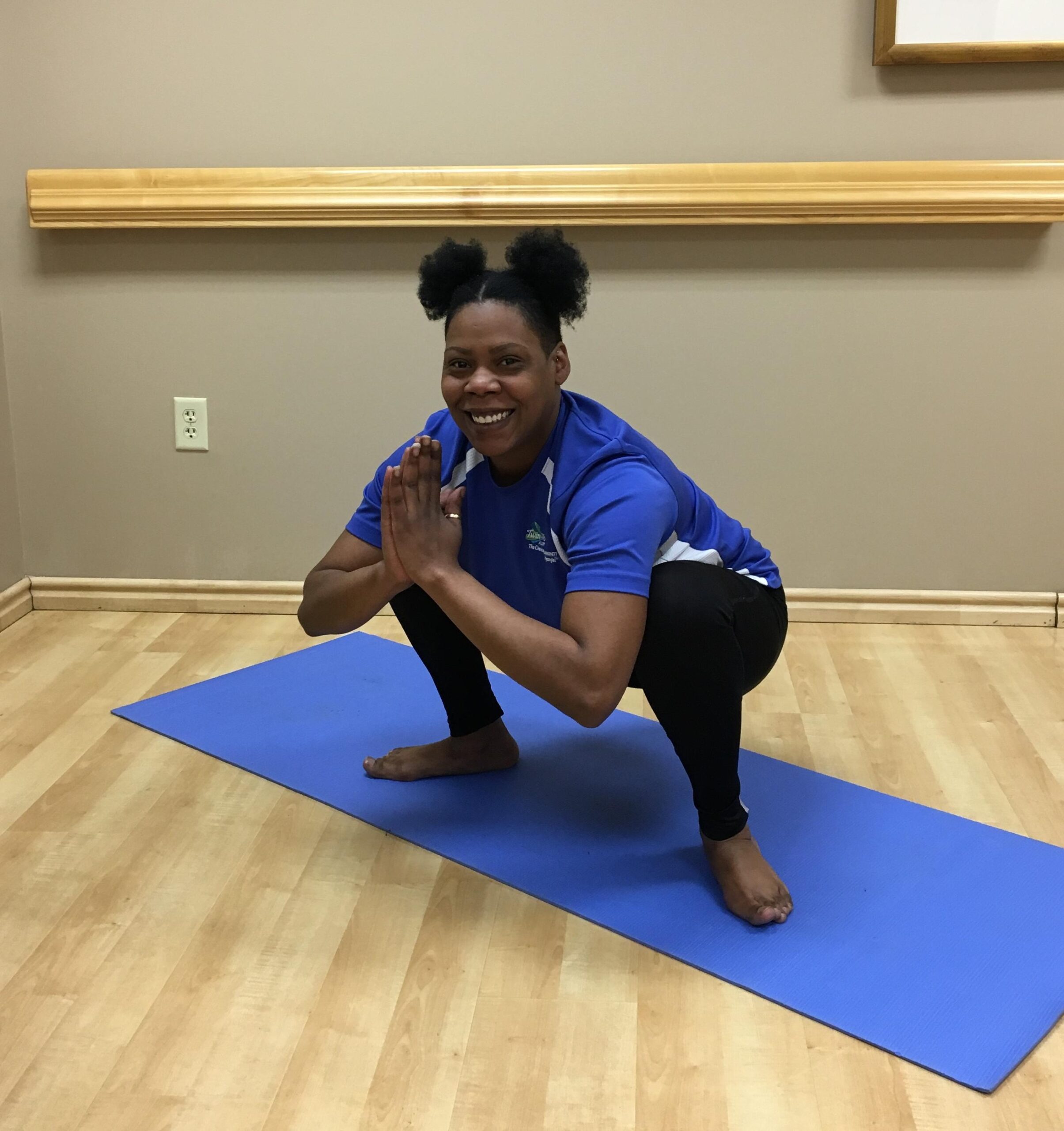 woman squatting on yoga mat with arms bent, palms pressed together