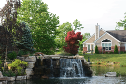 closeup of pond with waterfall. villa home in background