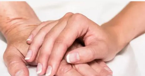 young person's hand laying on senior's hand