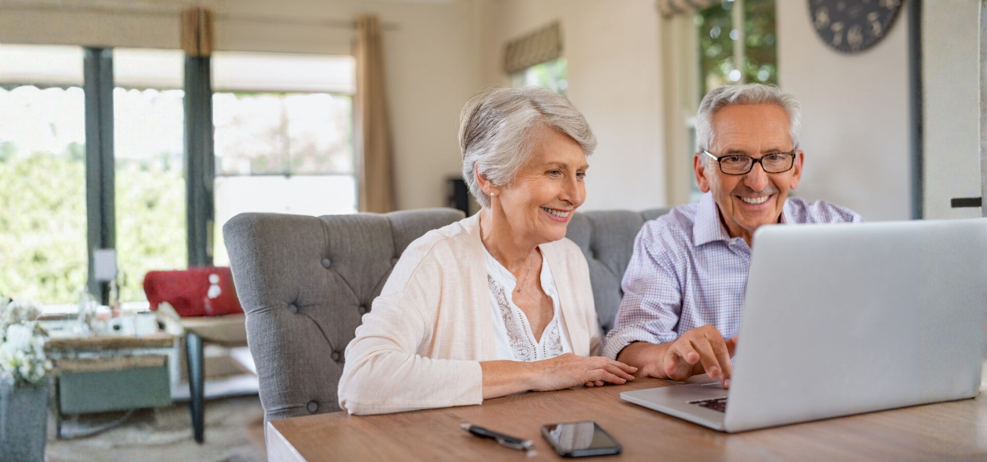 Older couple using a laptop together at home as part of a social media guide for seniors.