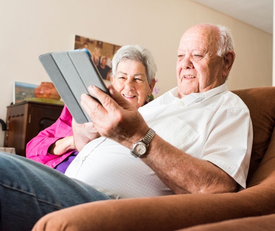 Senior couple sitting on couch while looking at tablet together