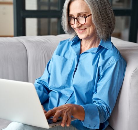 A woman sitting on the couch with a laptop