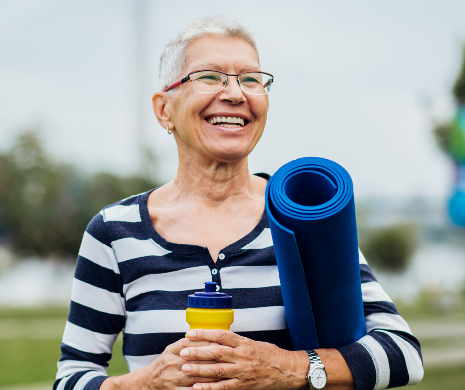 Senior woman smiling holding yoga mat