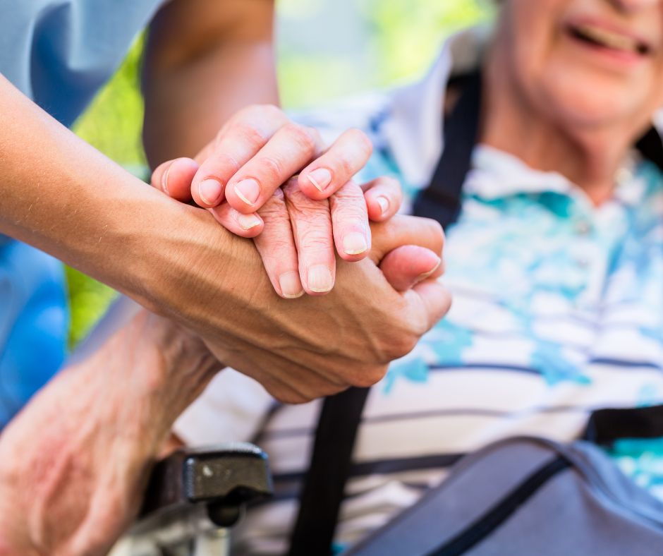 physical therapist holding senior's hands offering assistance