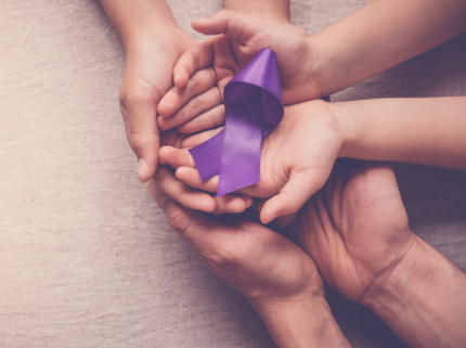Hands holding purple ribbon