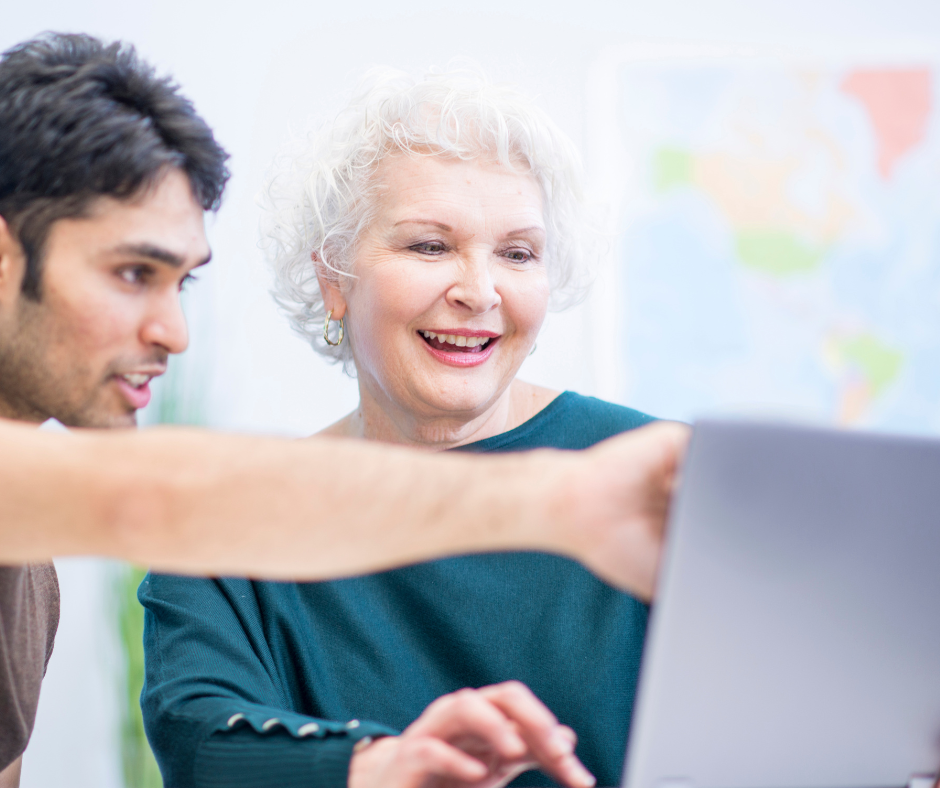 senior woman with young adult working at computer