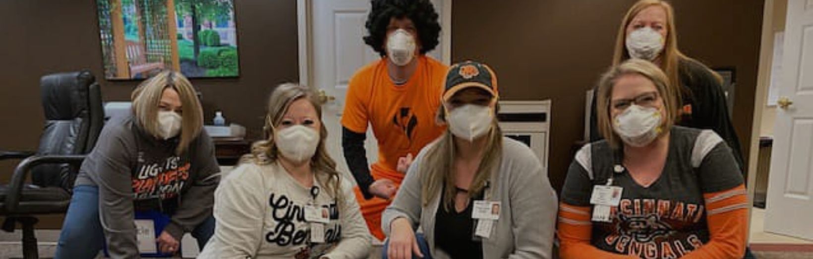 employees wearing ID badges pose together all are wearing masks
