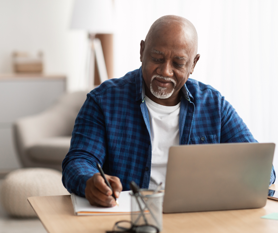 Senior man working at laptop with notebook