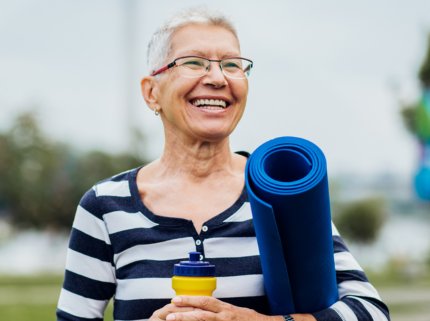 Older adult woman with yoga mat smiling
