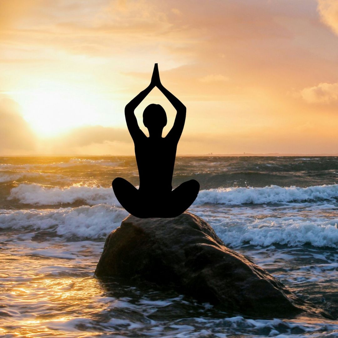 a woman performing yoga on a rock