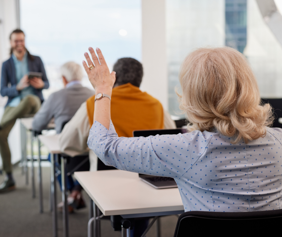 Older adult woman raising hand in seminar