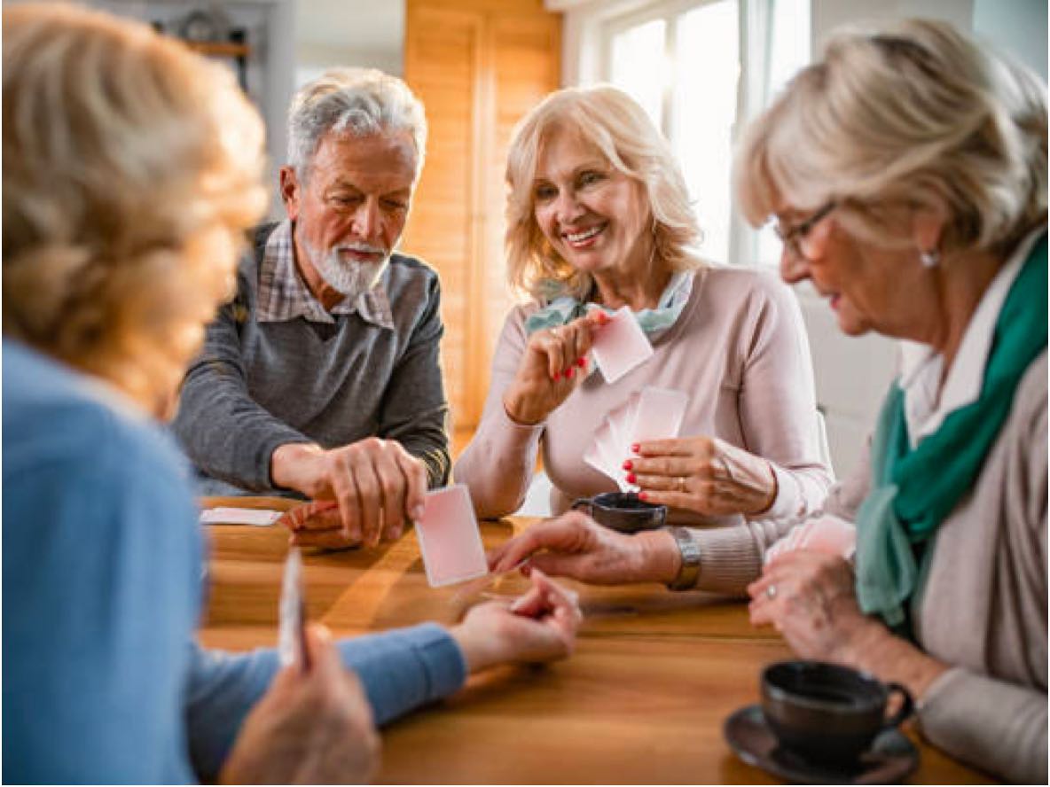 group of seniors playing cards and having coffee or tea in retirement community
