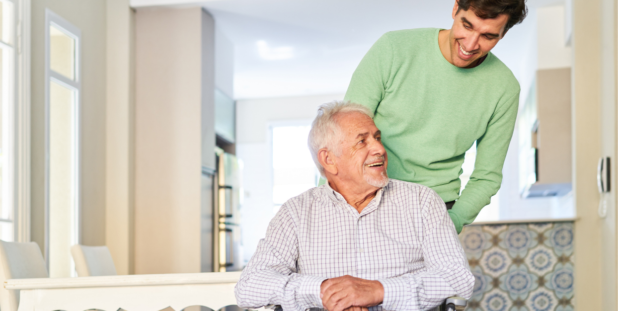 Young adult male caregiver laughing with senior man