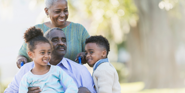 African American family with gentleman in wheelchair and wife behind him. Spending time with their grandchildren.