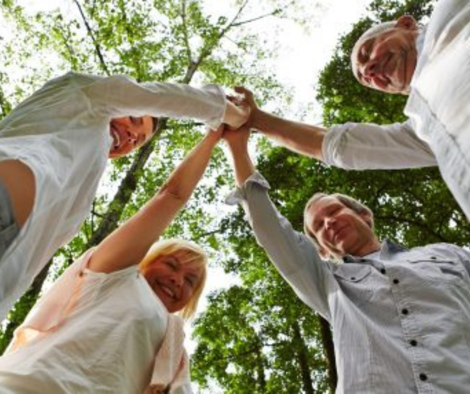 group of diverse seniors with hands in the middle signaling teamwork