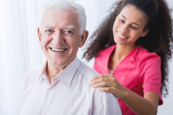 Female nurse touching senior man's shoulder both smiling