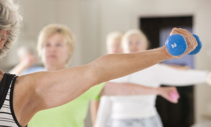 Senior woman lifting weight in exercise class