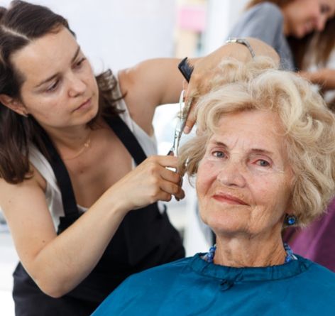 Senior woman getting her hair cut by female stylist