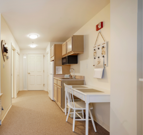 kitchenette area of Wesley Ridge assisted living apartment with small table for eating, refrigerator and sink