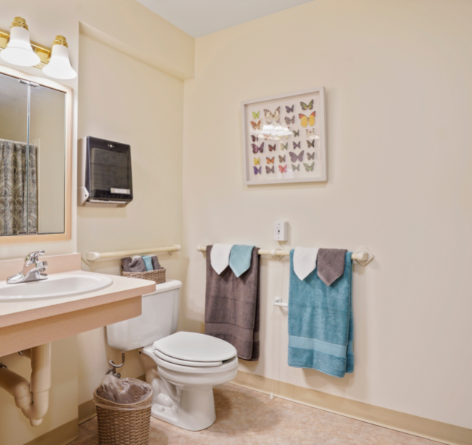 bathroom of Wesley Ridge assisted living apartment with blue and gray bath towels, decor, sink and toilet