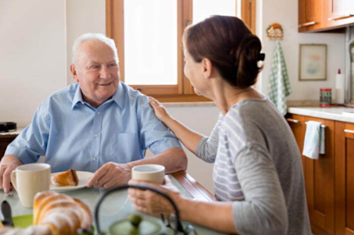senior man having breakfast with assisted living caregiver
