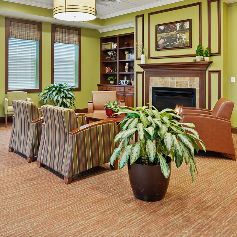 interior view of Wesley Ridge Robert A. Barnes rehabilitation center common area with ferns, fireplace and seating