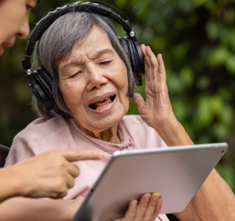 senior woman with headphones on listening to music while looking at an iPad