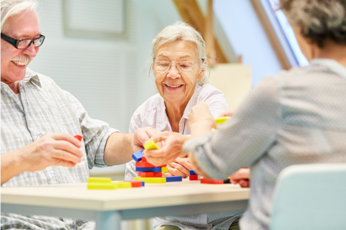 group of seniors smiling while playing a building blocks game