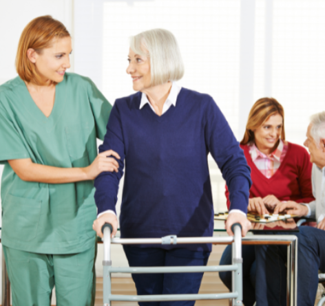 senior woman using a walking while looking at female nurse who is helping her walk