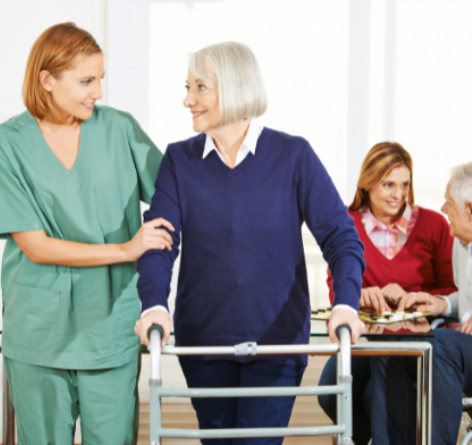 senior woman walking while looking at female nurse who is helping her in rehabilitation