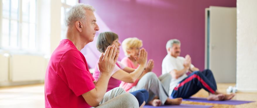 Seniors in a yoga class with hands folded in namaste