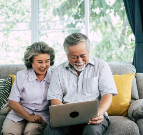 Senior Asian couple looking at laptop on couch