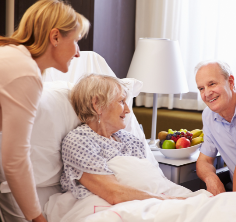 Senior woman in hospital bed with son and daughter around her