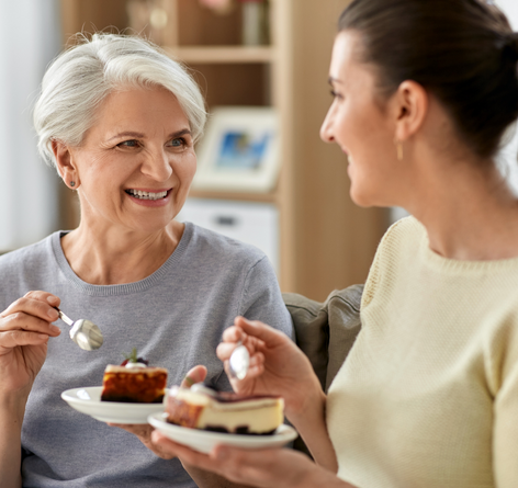 senior woman and her daughter visiting while having cake together