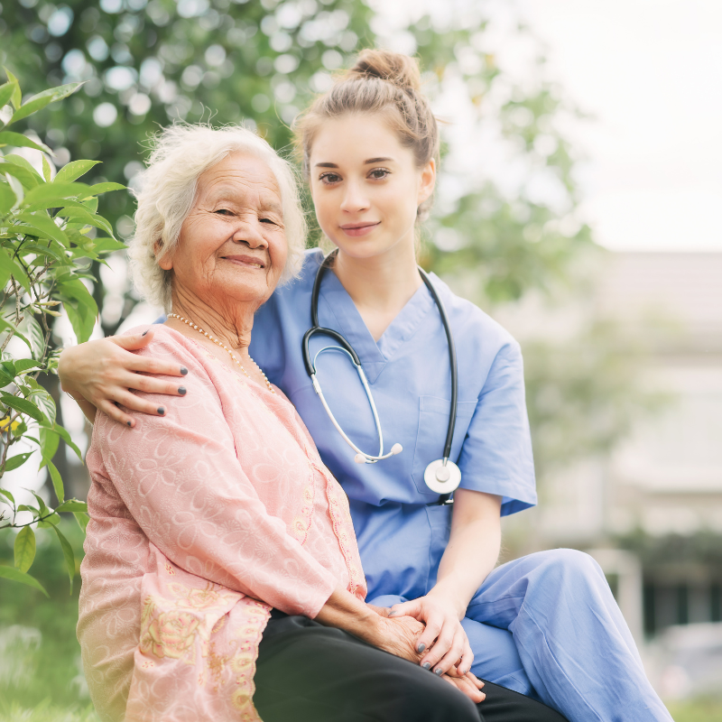 Senior Asian woman with young female nurse who has her arm around her
