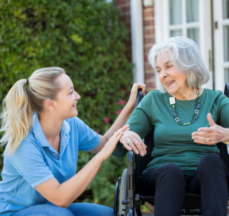 Senior woman in wheelchair with female nurse kneeling next to her