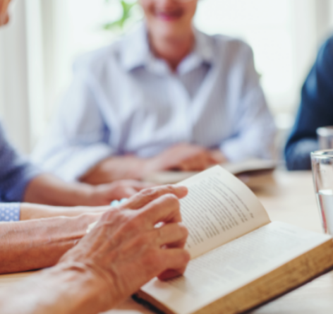 Seniors around a table with closeup of hands reading the bible