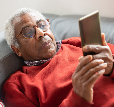 senior man who is sick laying down about to make a phone call